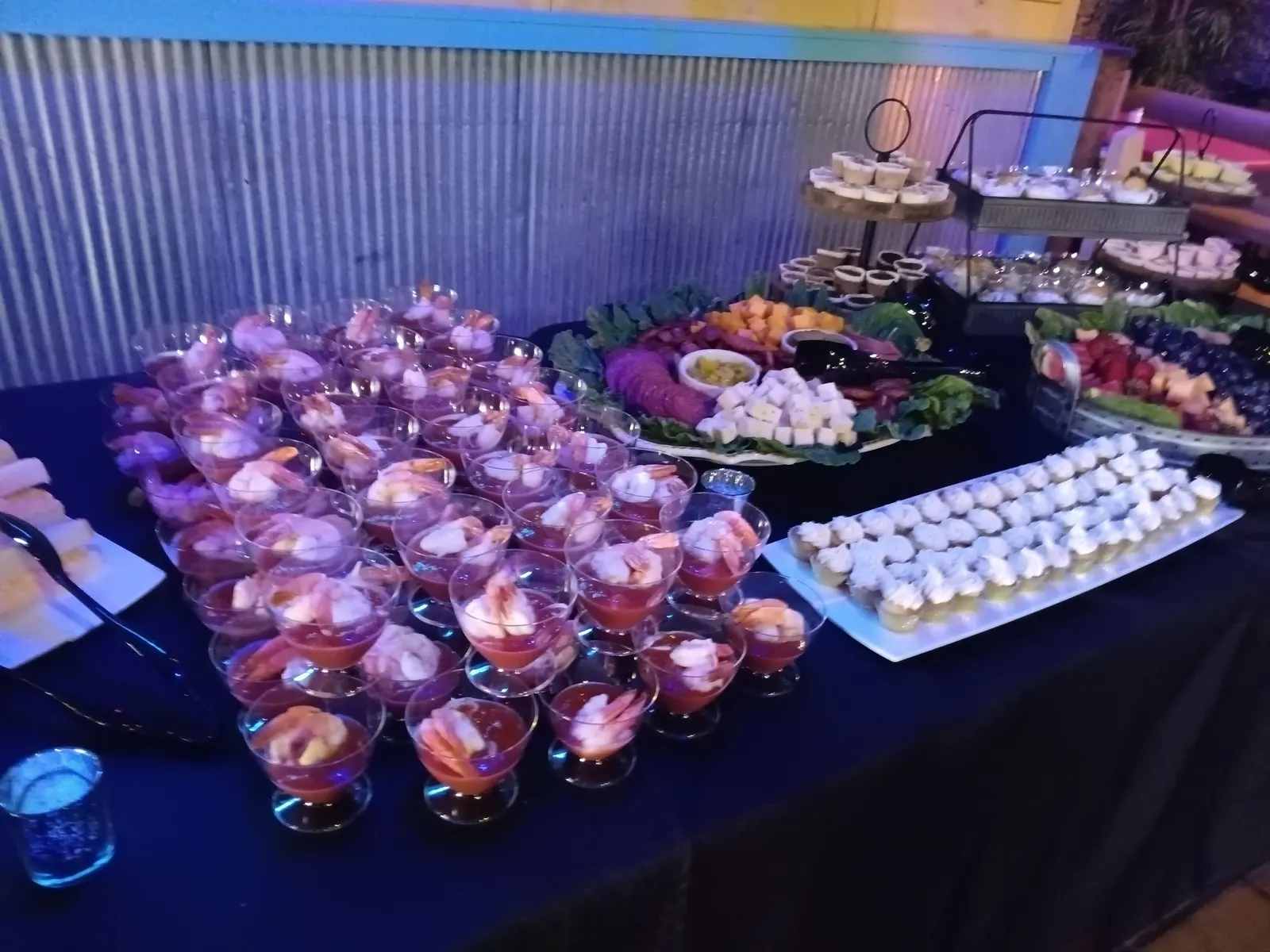 Rows of shrimp cocktail cups beside a meat and cheese tray